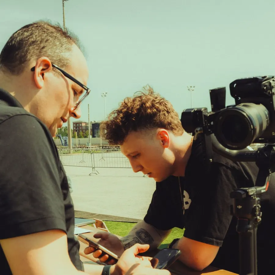 Deux membres de l'équipe qui revoient un plan sur un téléphone lors d'un tournage extérieur