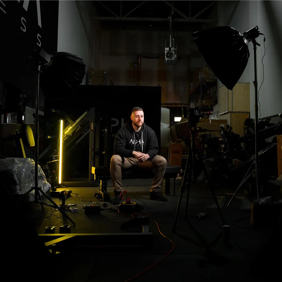 Portrait en studio dans un entrepôt de gym, entouré de boîtes à lumière et d'un tube lumineux jaune