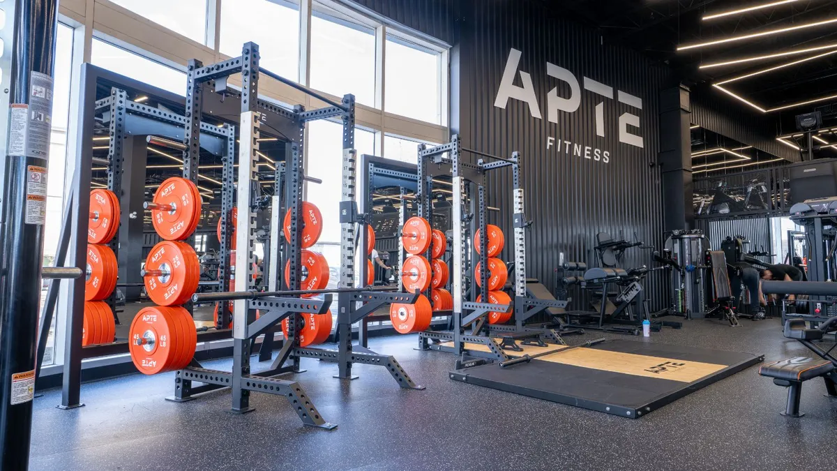 Salle d'entraînement APTE Fitness avec racks et disques orange