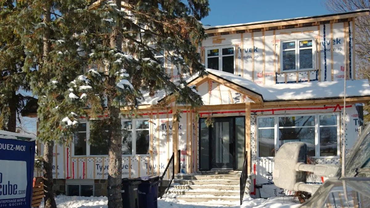 Maison en construction sous la neige, membrane Tyvek et charpente apparente