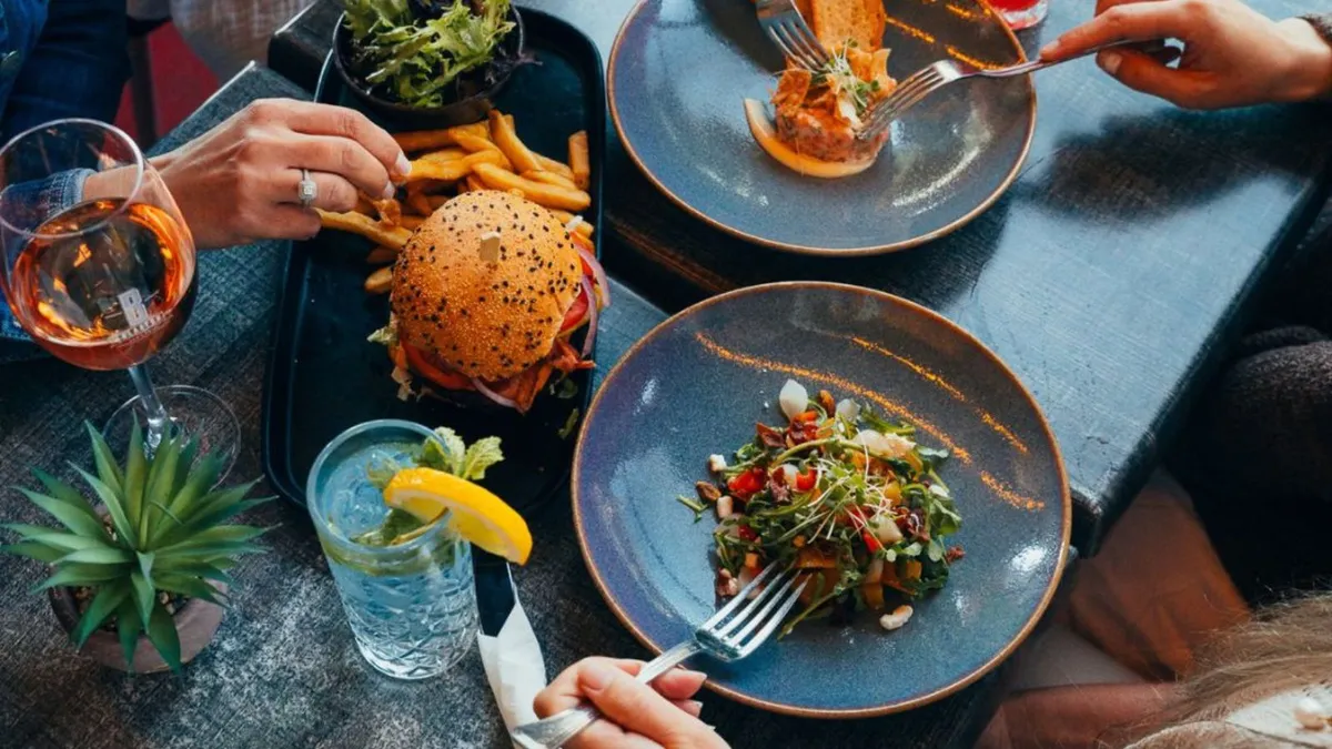 Table de restaurant vue de haut : burger, frites, salade et verre de rosé