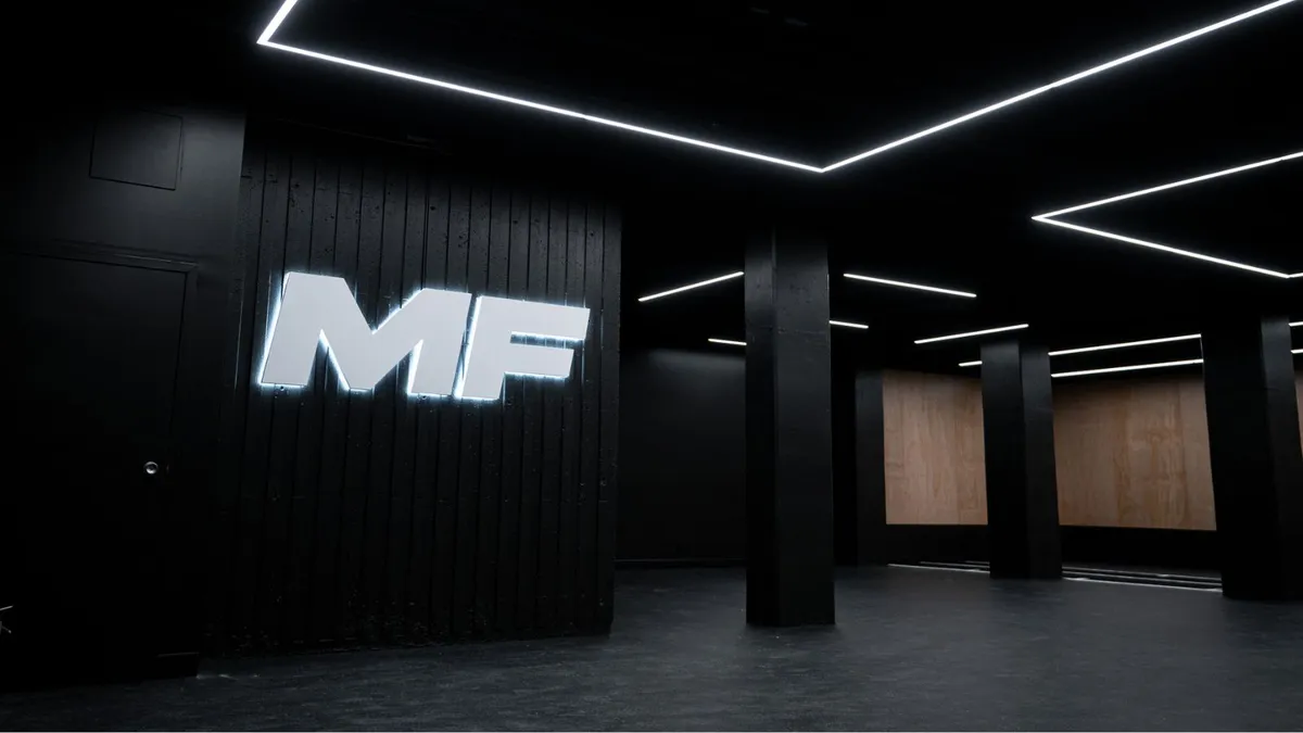 Salle d'entraînement Maxi-Forme, logo MF lumineux sur un mur noir
